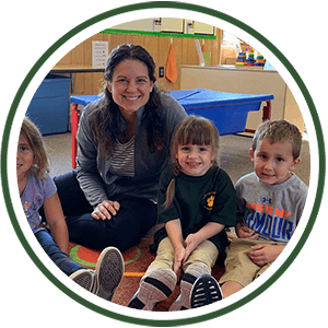 Teacher with Pre schoolers during reading time on the floor of the classroom. Image is cropped into a circle.