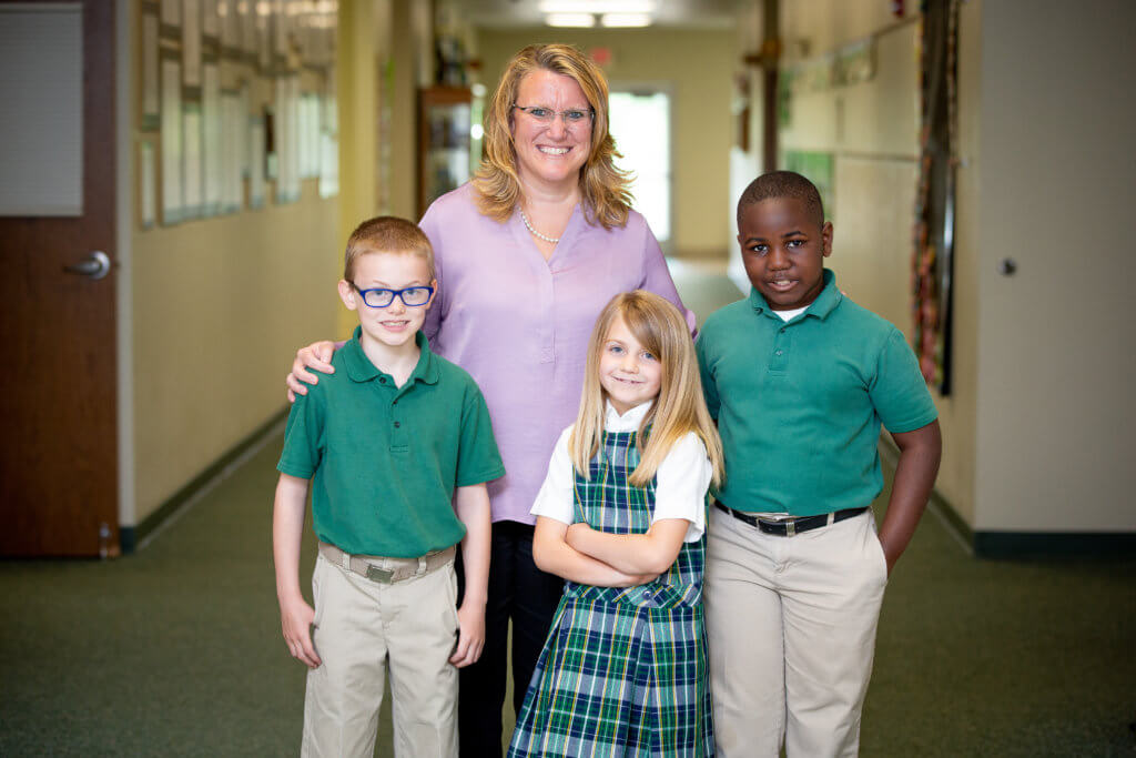 Colleen Vogt with three students in hallway